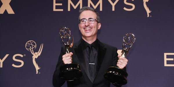 John Oliver com suas duas estatuetas na mão por ter ganhado como melhor apresentador de talk show e melhor programa de talk show