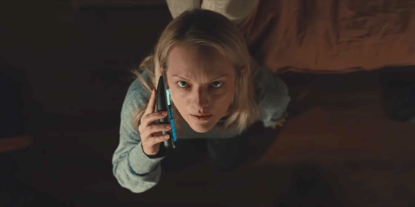 Elisabeth Moss com um celular na mão, olhando para cima aflita